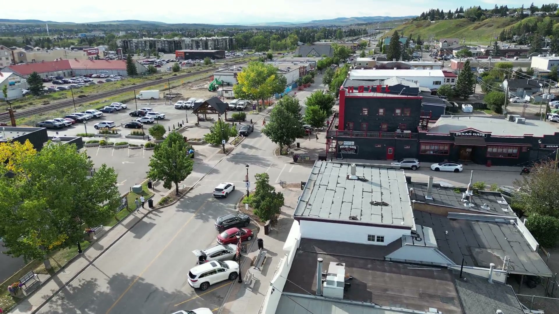 The camera tilts from the shop's roof out across downtown Cochrane to the rail line and the foothills