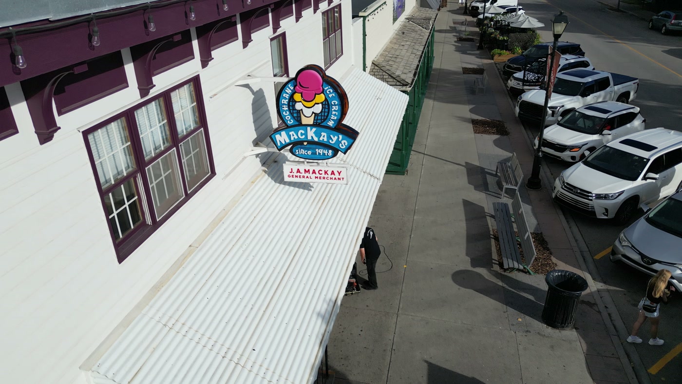 The roundel above the shop's corrugated awning, the sidewalk and the angled parking below