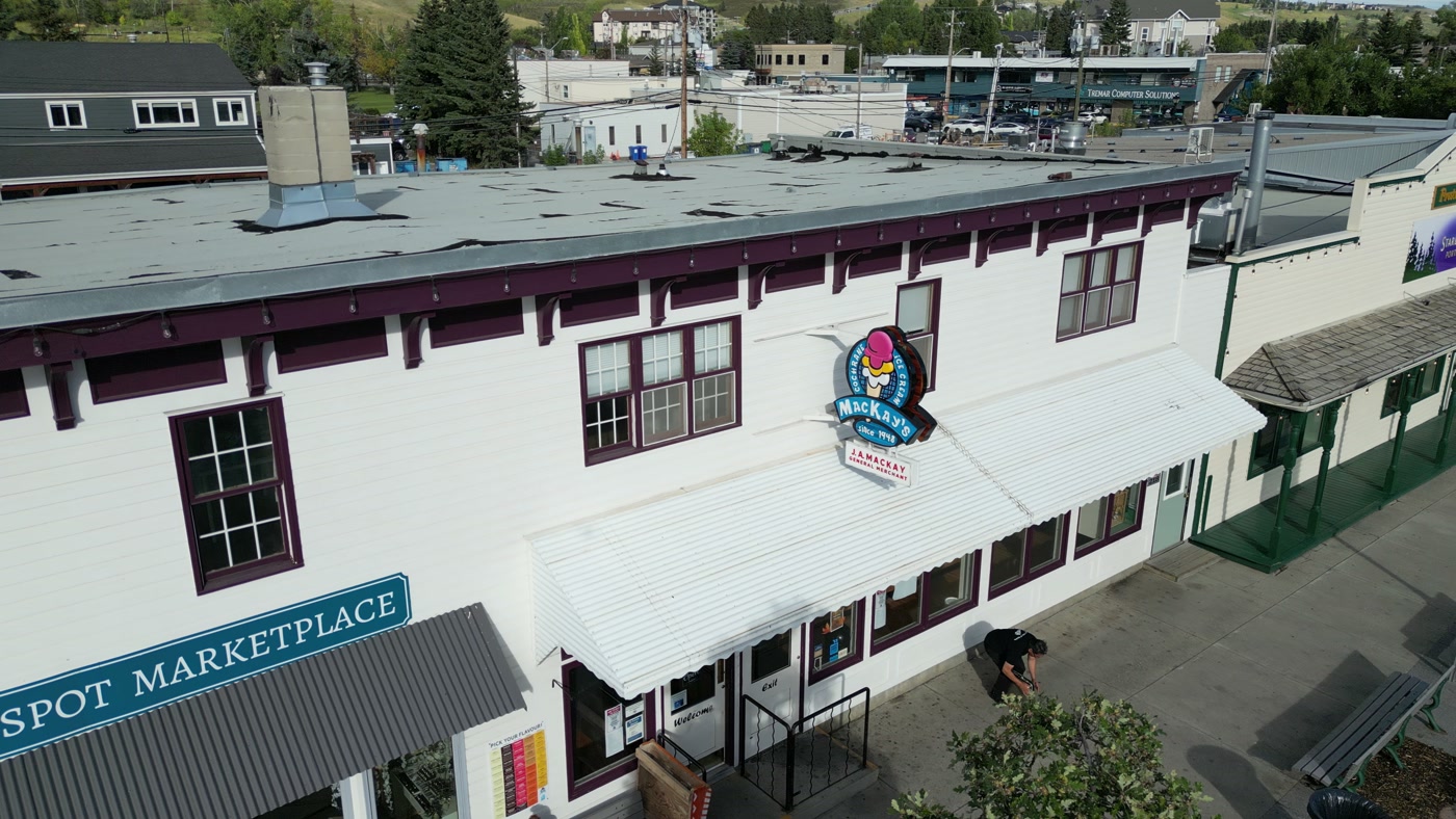 The white two-storey block on 1st Street West, its awnings and upper windows, the MacKay's roundel at the far end