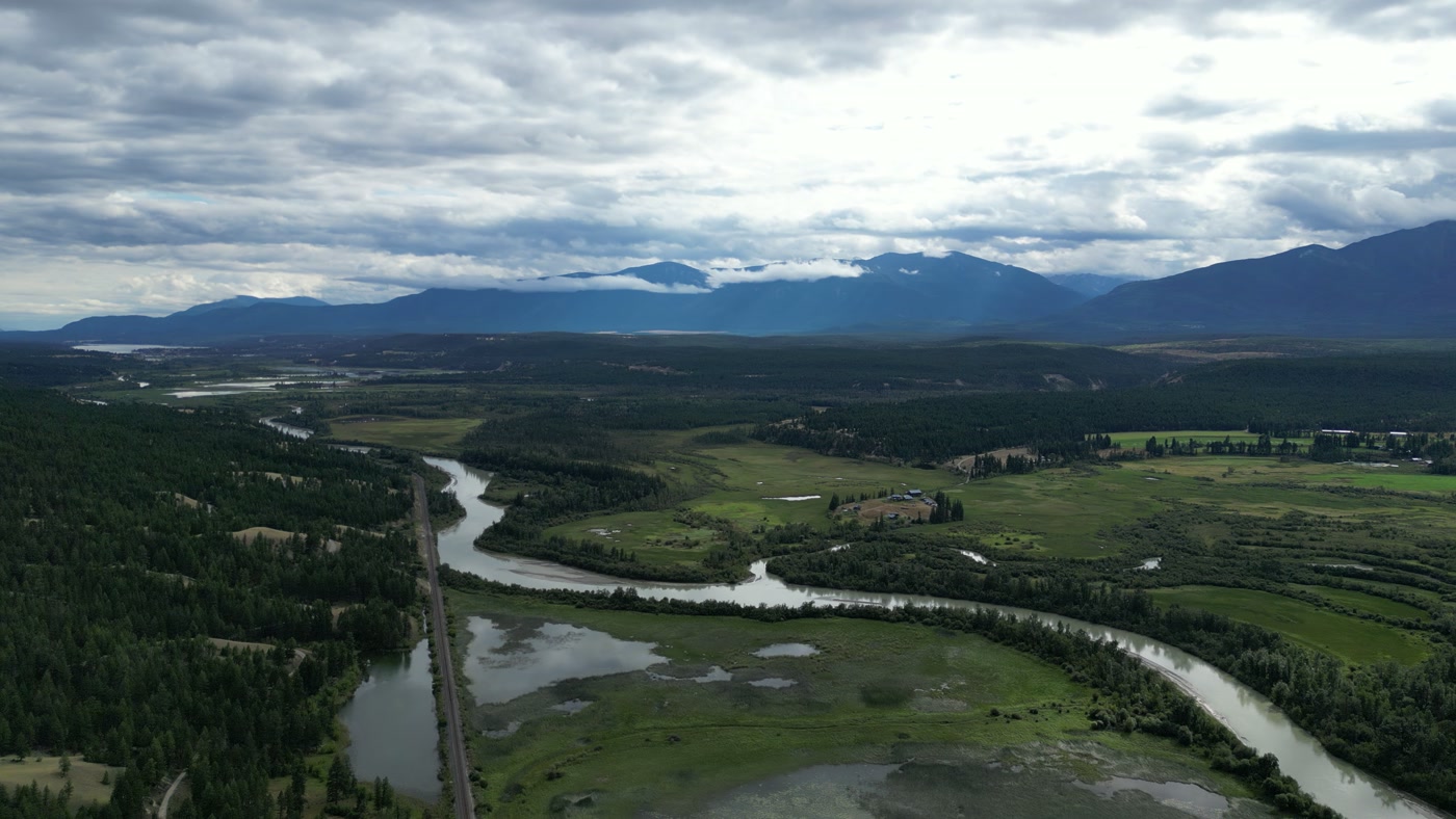 The Columbia Valley at Radium Hot Springs from the top of the climb: the river's bend, the railway running straight toward the horizon, fields and farm, the ranges on either side