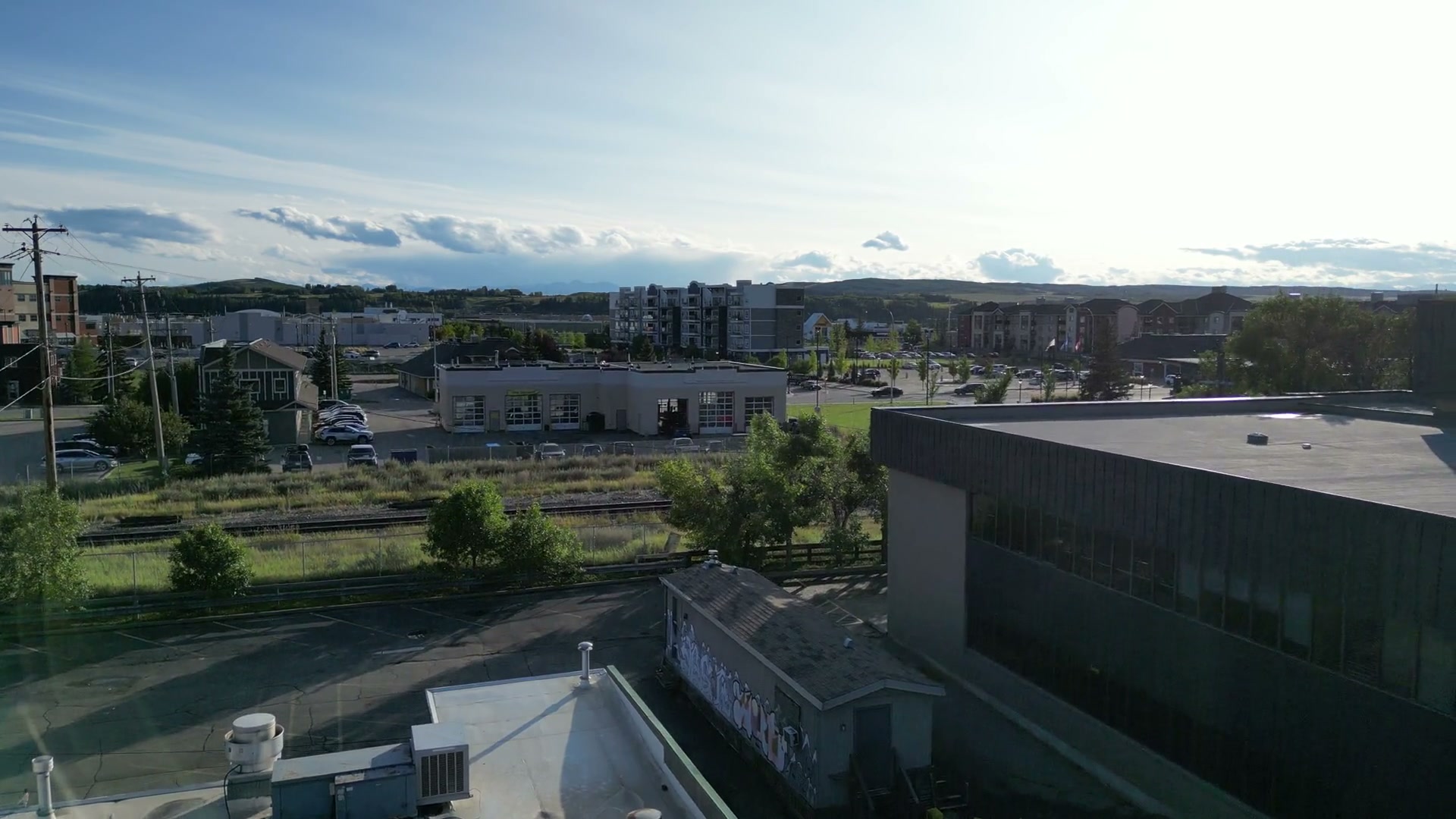 The camera rising from the Sunny Side Up sign in Cochrane over the parapet and the flat roof, the low sun flaring at the edge, until apartment blocks and hills come into view