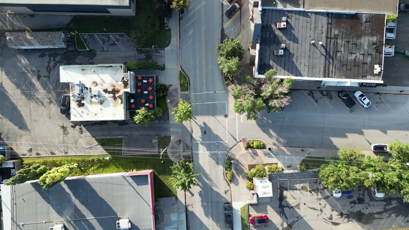 The patio of Sunny Side Up in Cochrane from directly above: red square tables inside a low wall, the white flat roof and its rooftop units beside it