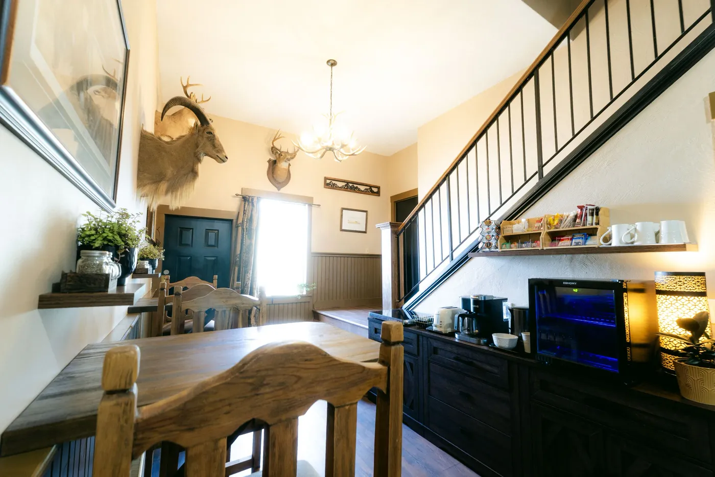 A dark-cabinet kitchen with a mounted deer head and a staircase rising beside it