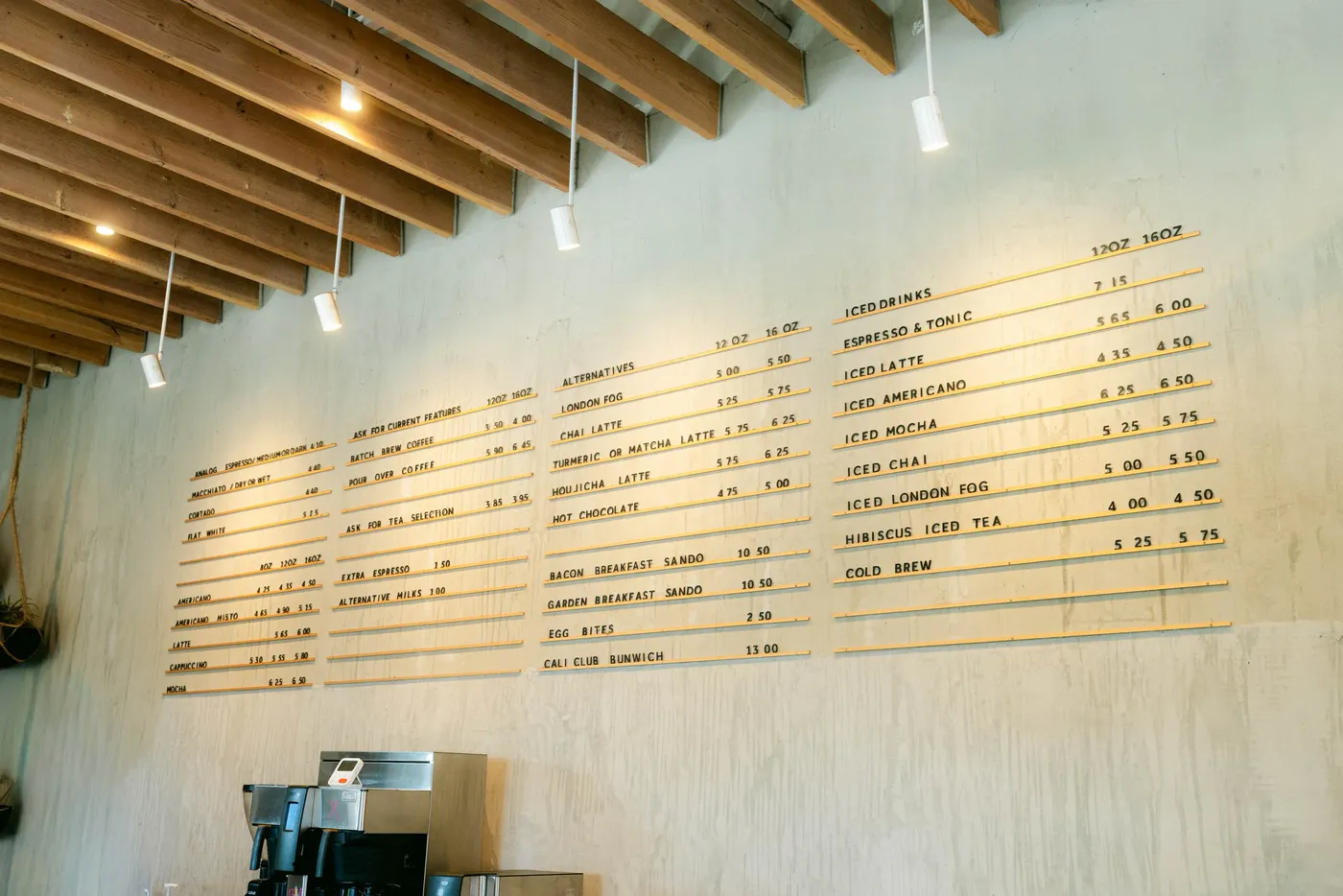 A long hand-lettered menu board above the espresso bar of a bright cafe