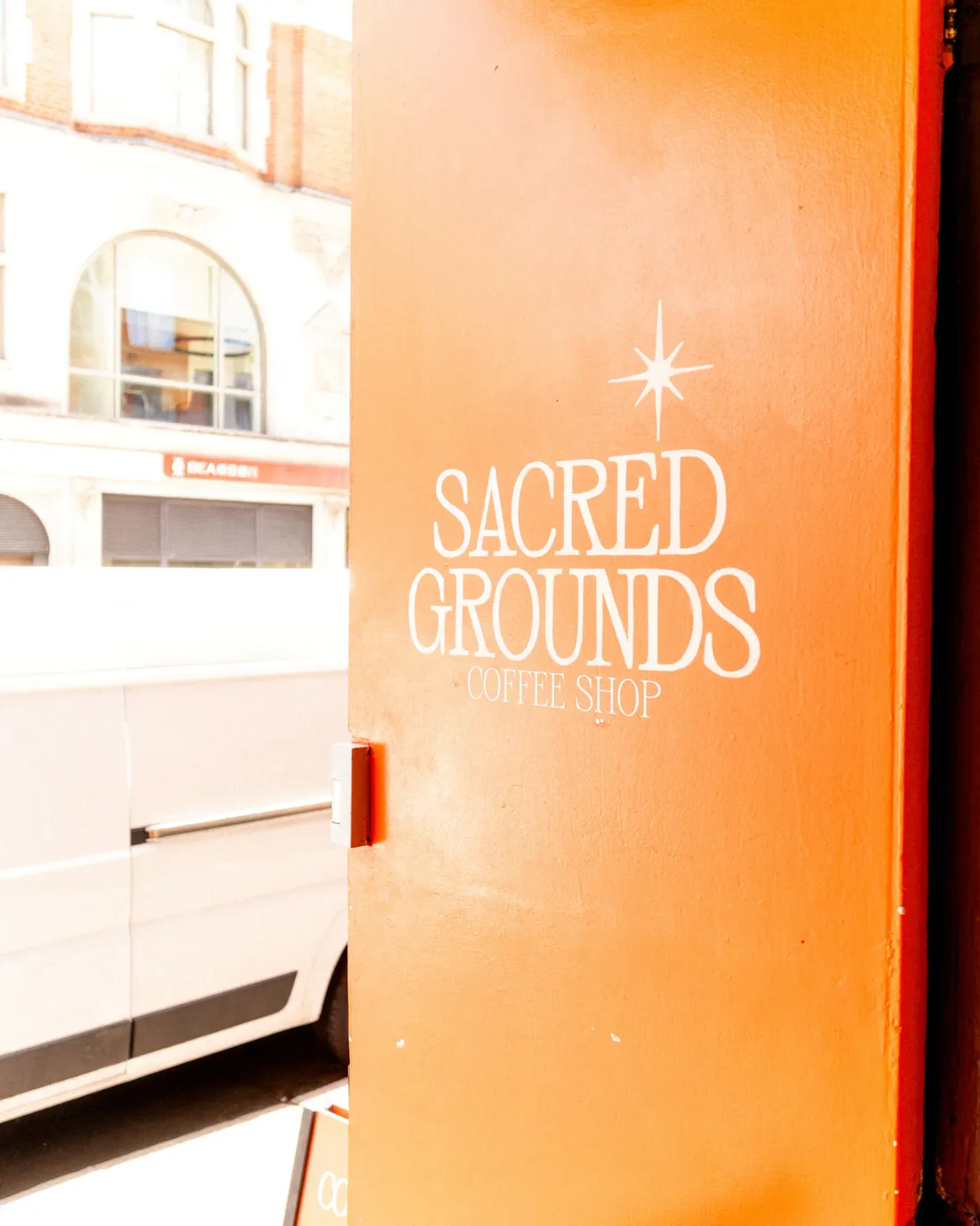 A bright orange coffee-shop door painted with the shop's name on a city street