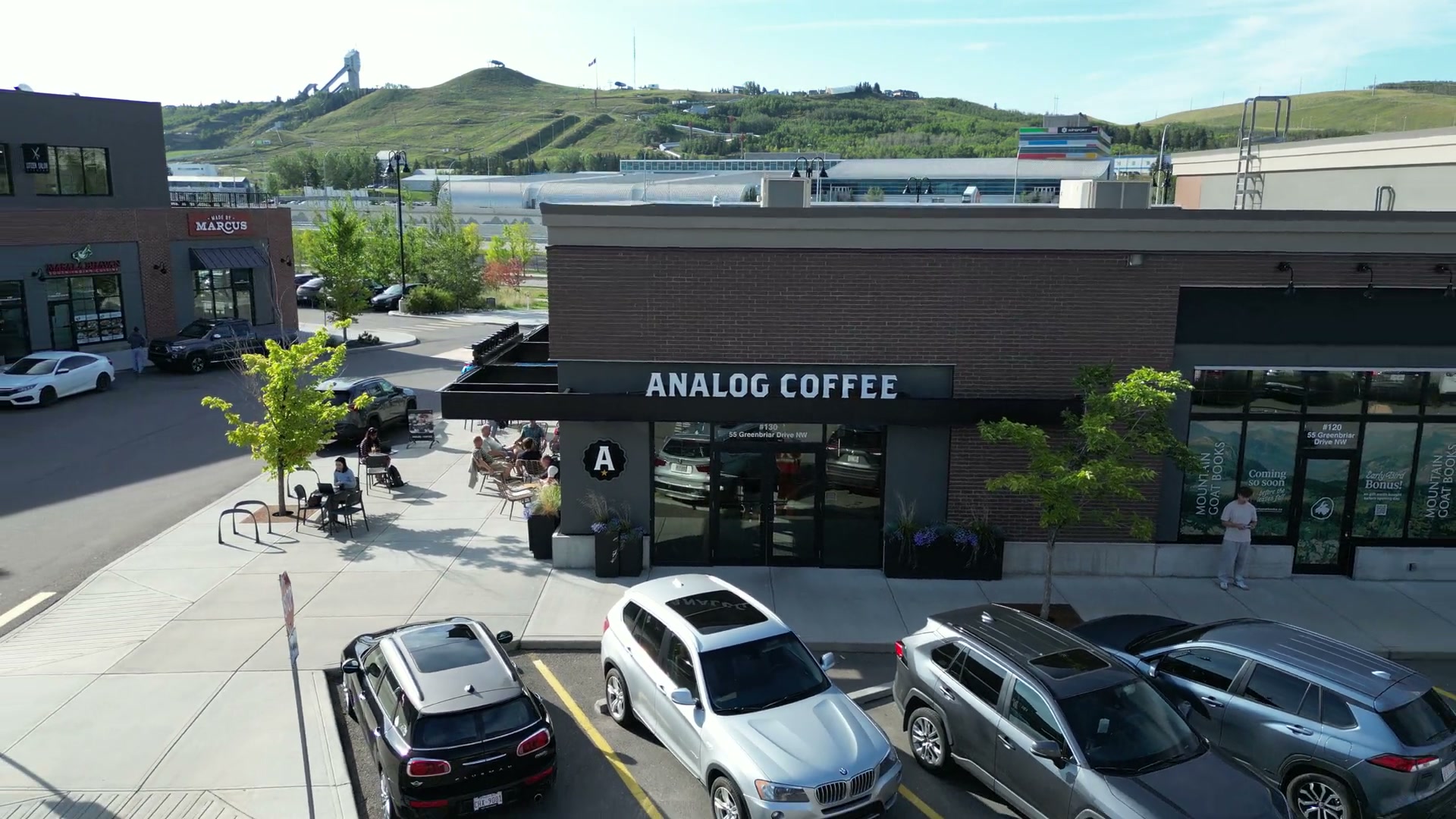 Pulling straight back from the ANALOG COFFEE storefront until the hill across the Trans-Canada rises over the roofline