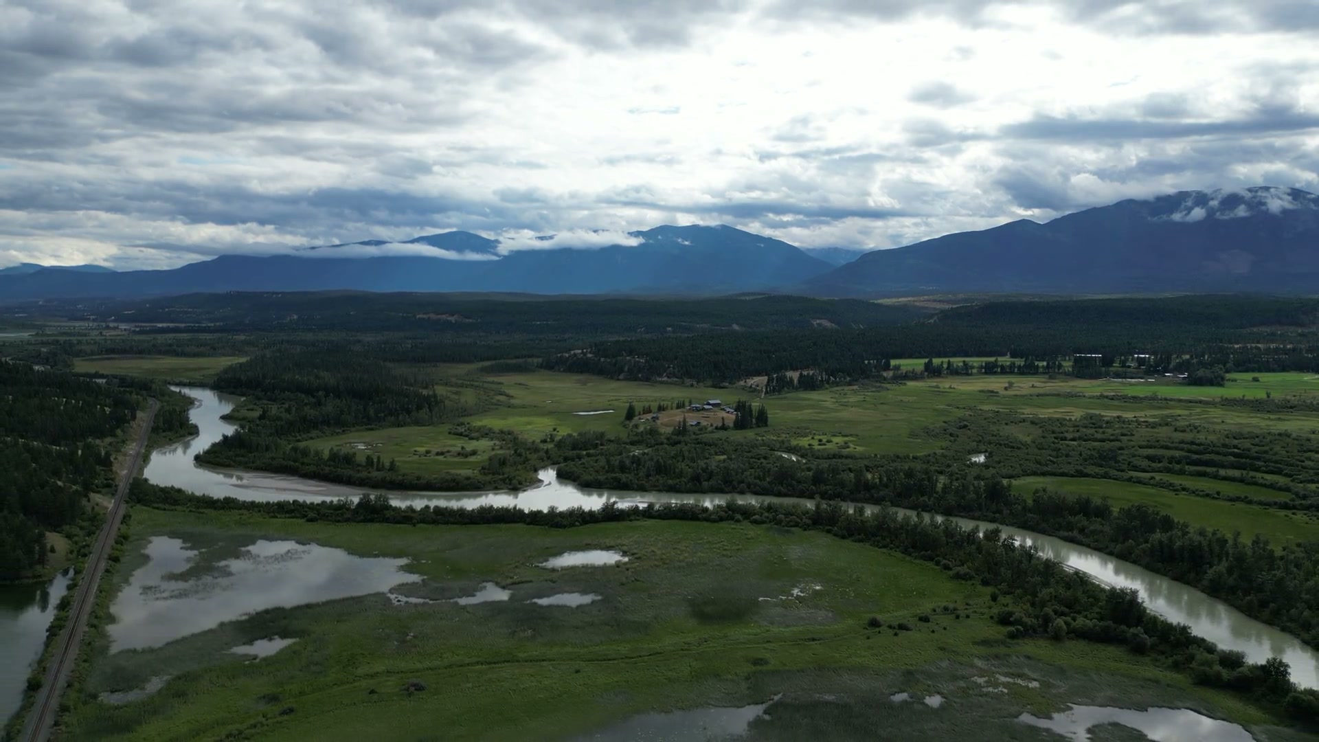 The Columbia River doubling back on itself through the wetland at Radium Hot Springs, a single-track railway running straight along its bank, oxbow ponds in the meadow