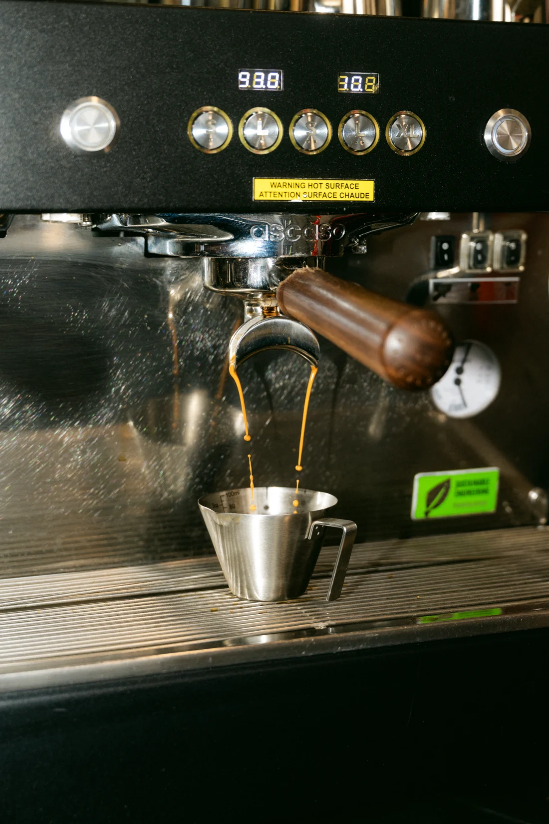 Espresso streams from a portafilter into a steel jug