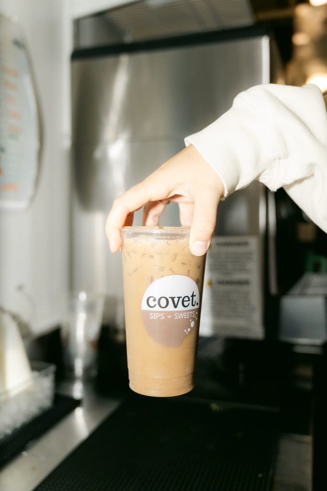 A hand sets an iced latte down on a black counter