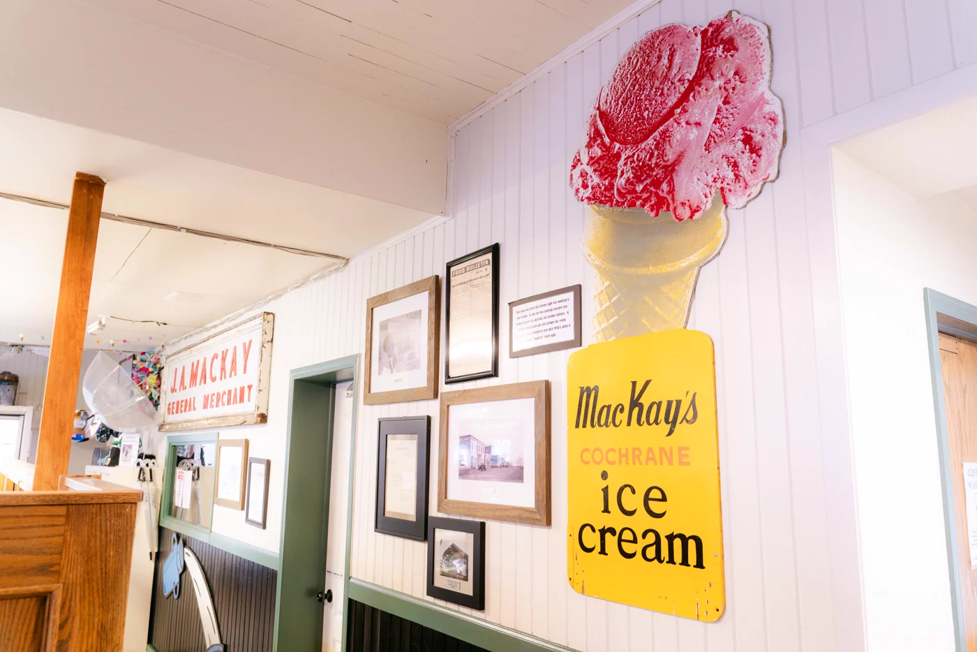 A painted ice cream cone sign and framed photographs on a shop wall