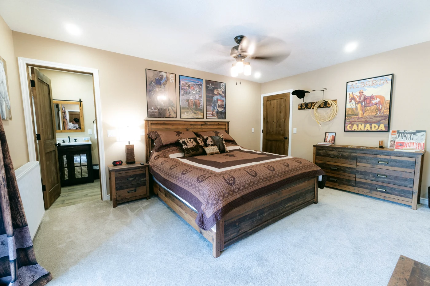 A lodge bedroom with a western quilt, a dresser and the ensuite door open