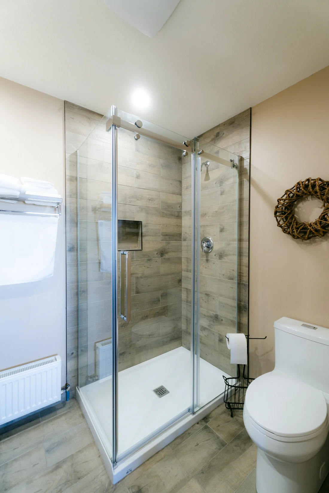 A glass shower and a wreath on the wall of a lodge ensuite