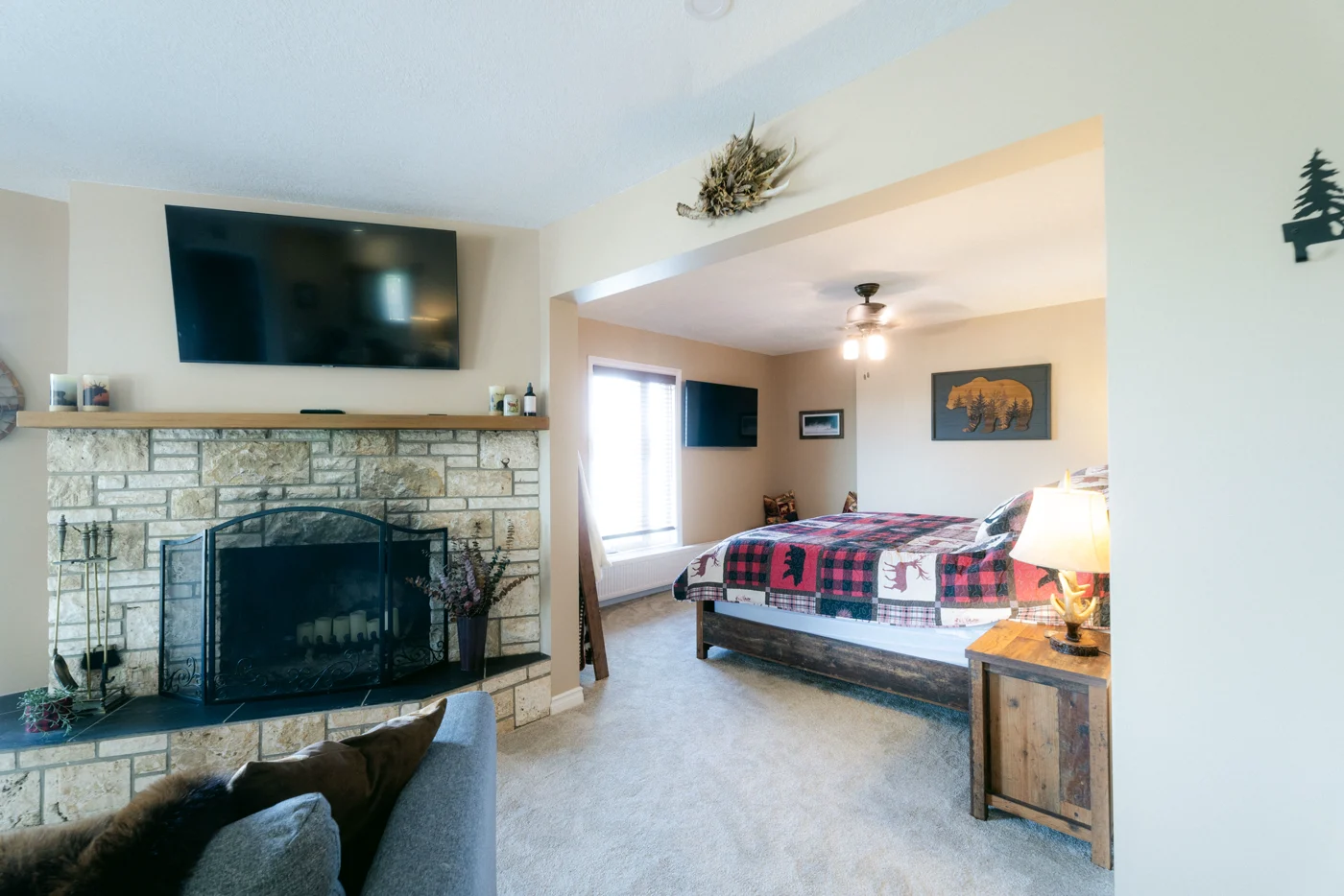 A stone fireplace and a bed with a check quilt in a lodge suite