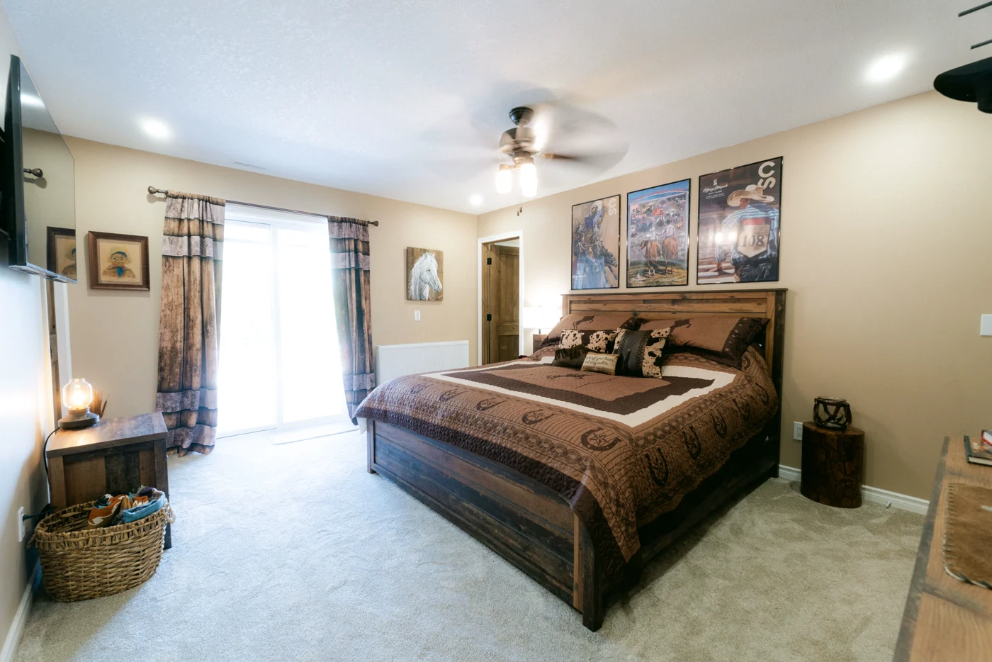A lodge room with a king bed, ceiling fan and curtained patio door