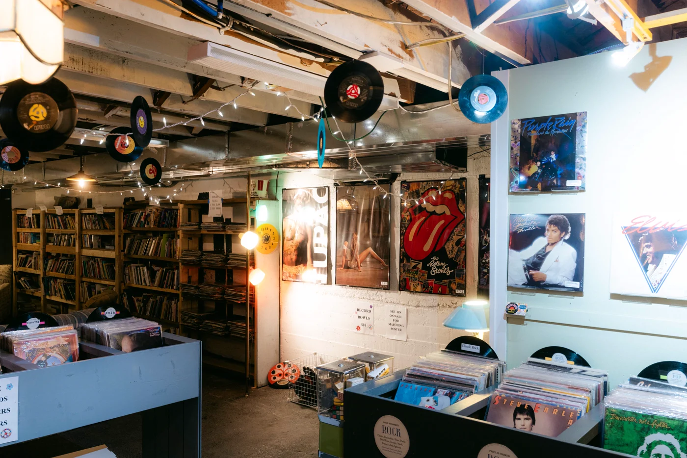 A record and book shop with vinyl hung from the ceiling and posters on the walls