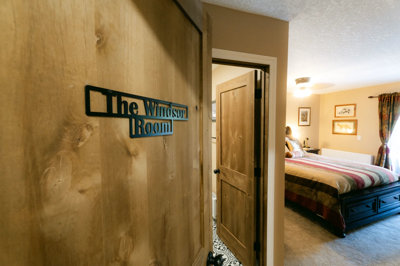 A wooden door with a metal plaque opens onto a lodge bedroom