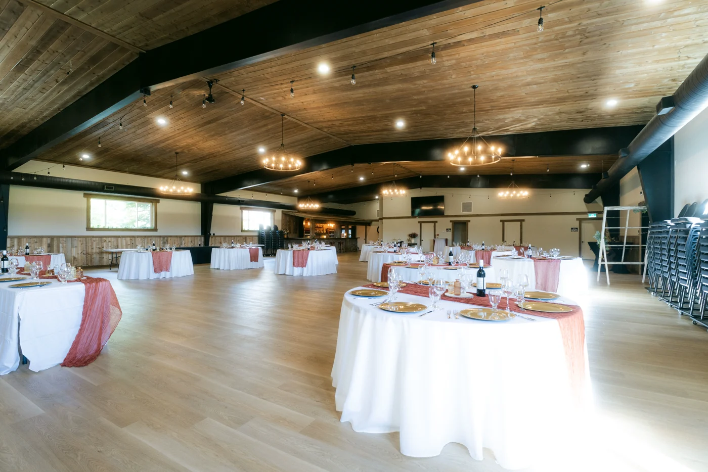 An event hall with round tables set for dinner under a timber ceiling