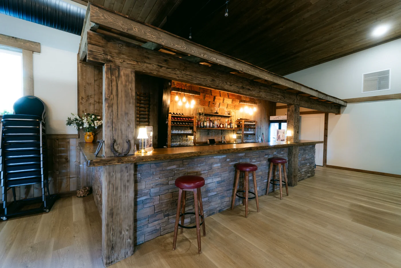 A barnwood bar with red stools in an event hall