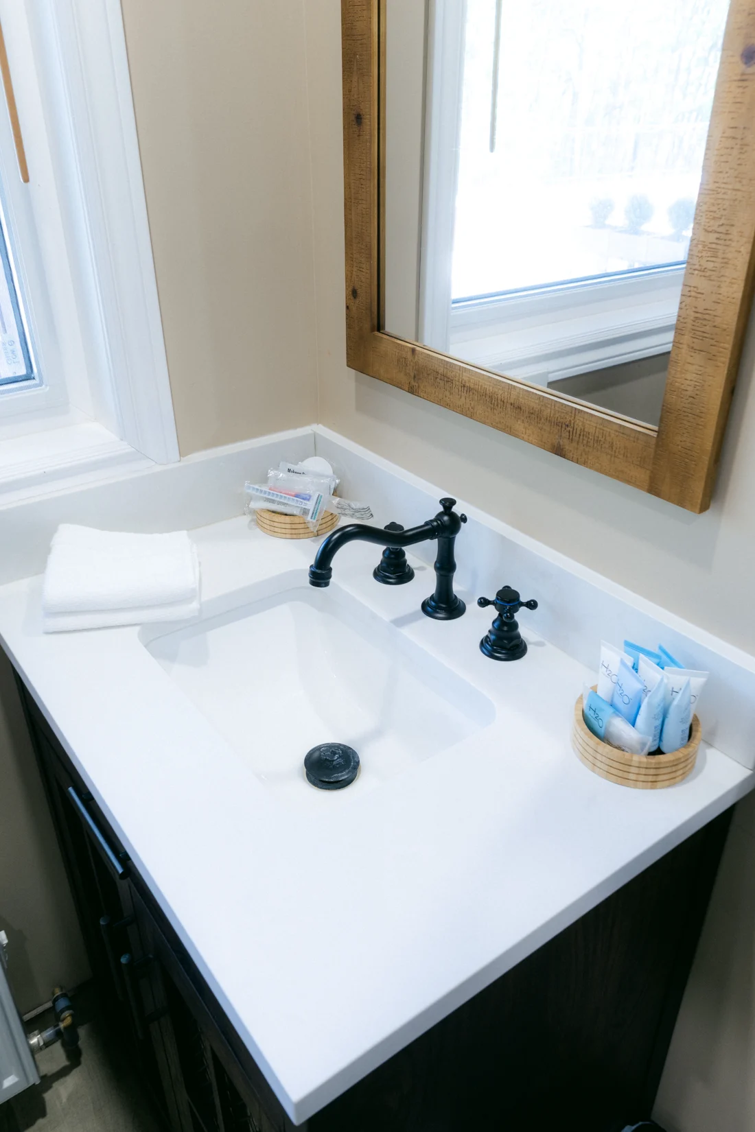 A white basin with black taps under a wood-framed mirror