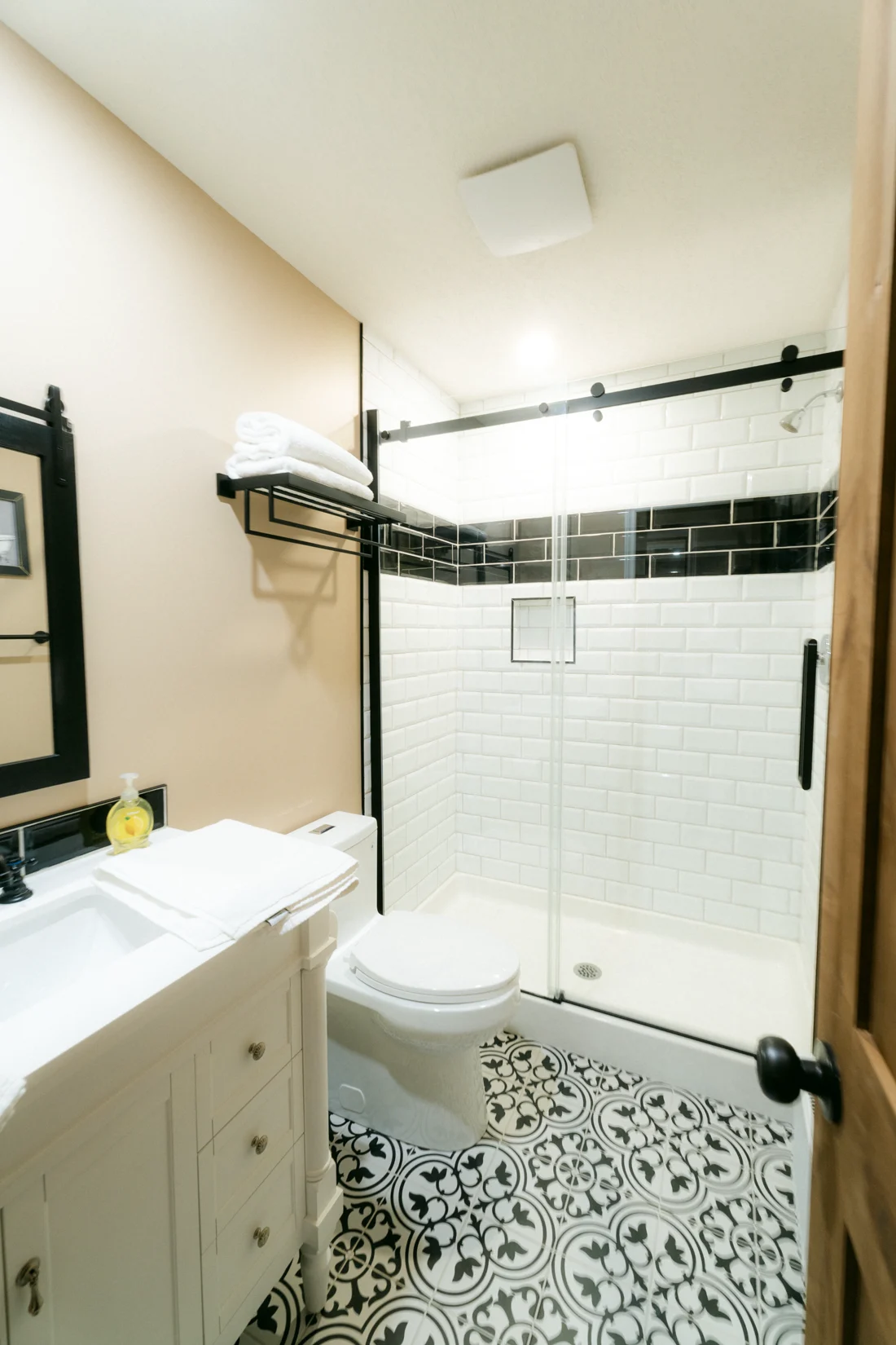 A bathroom with a black-framed shower and a patterned tile floor