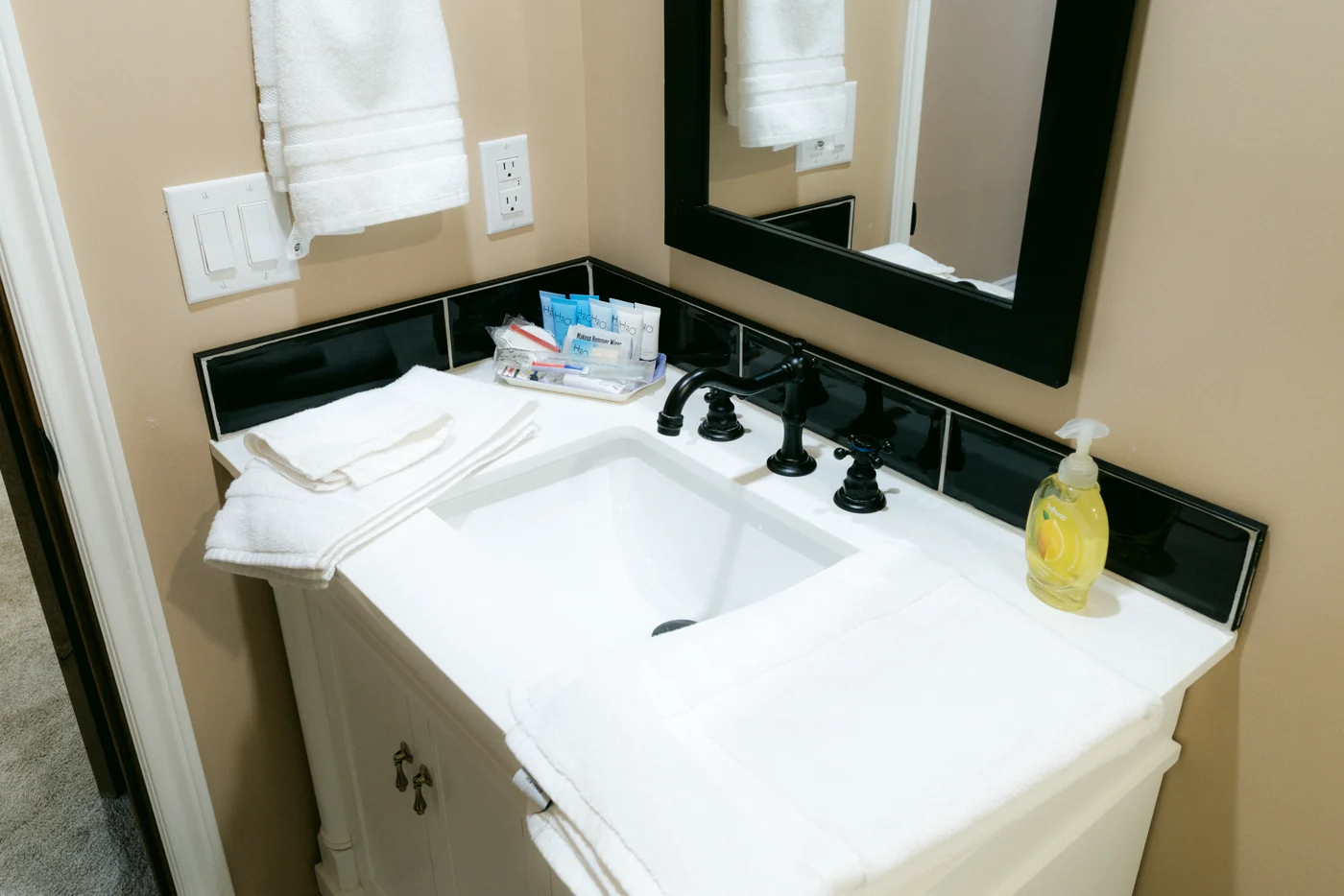Folded towels and black taps at a vanity under a black-framed mirror