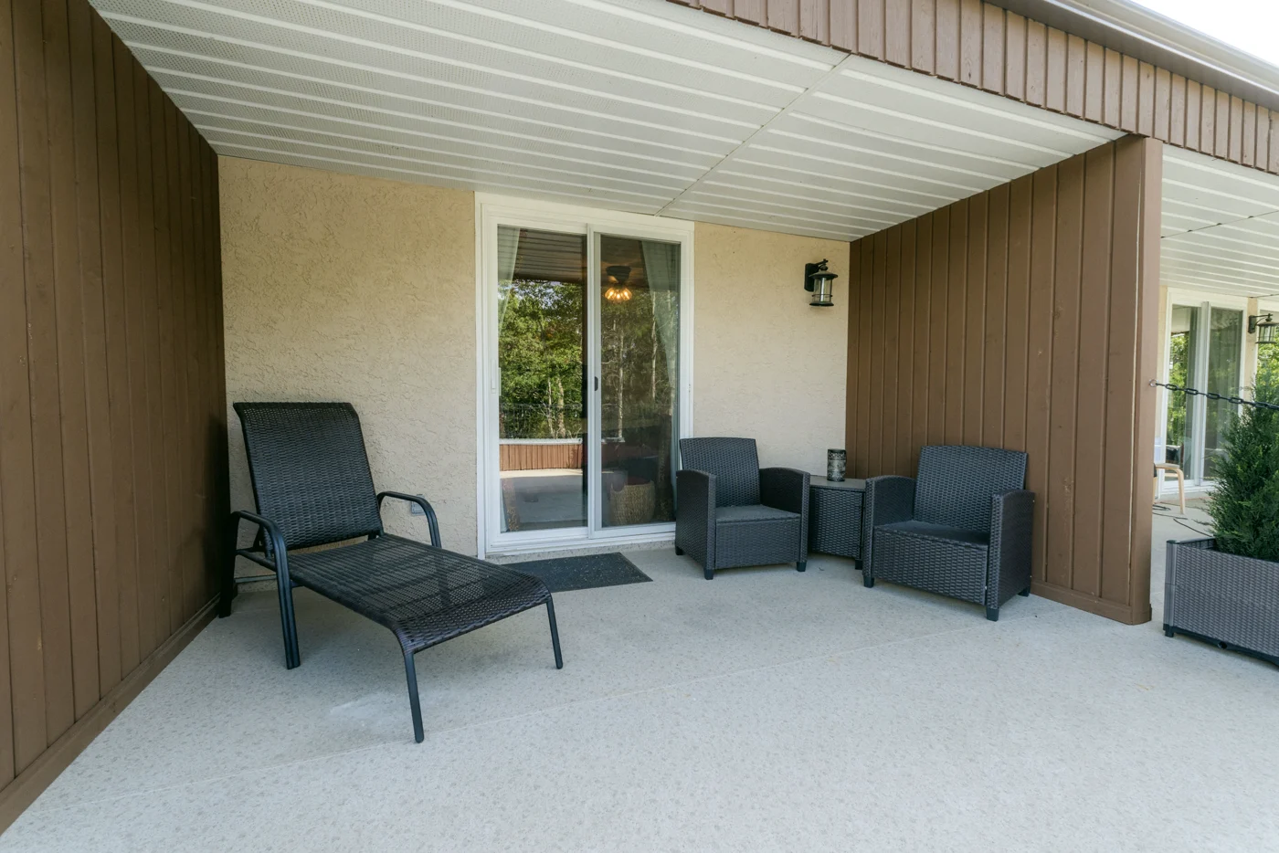 Loungers and armchairs on a covered patio outside a lodge room