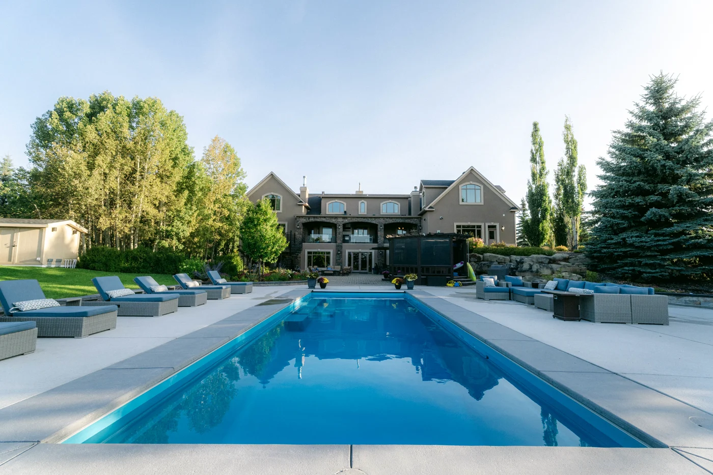A long rectangular pool straight on, loungers along one side and the house behind