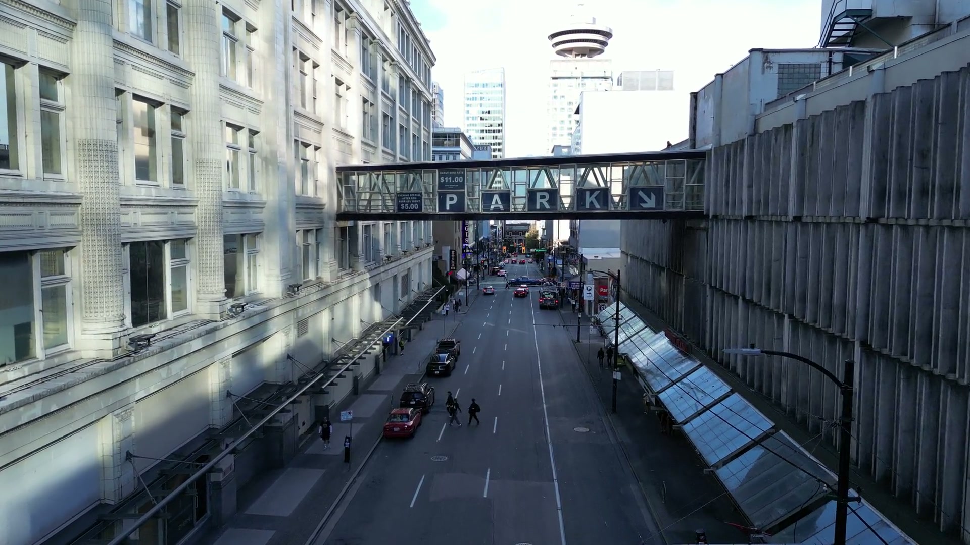 From the red signals at Seymour and West Georgia, north along Seymour Street between glass canopies and white terracotta, toward a skybridge spelling PARK over the road