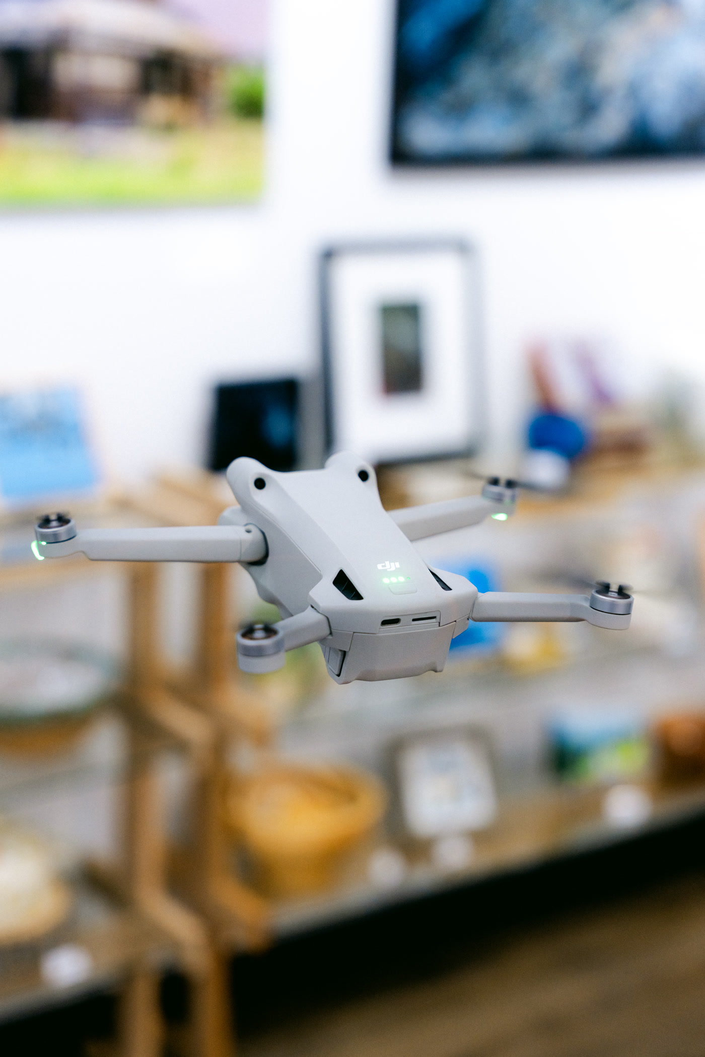 The small quadcopter hovering inside Route 22 Art Gallery, the shelves soft behind it
