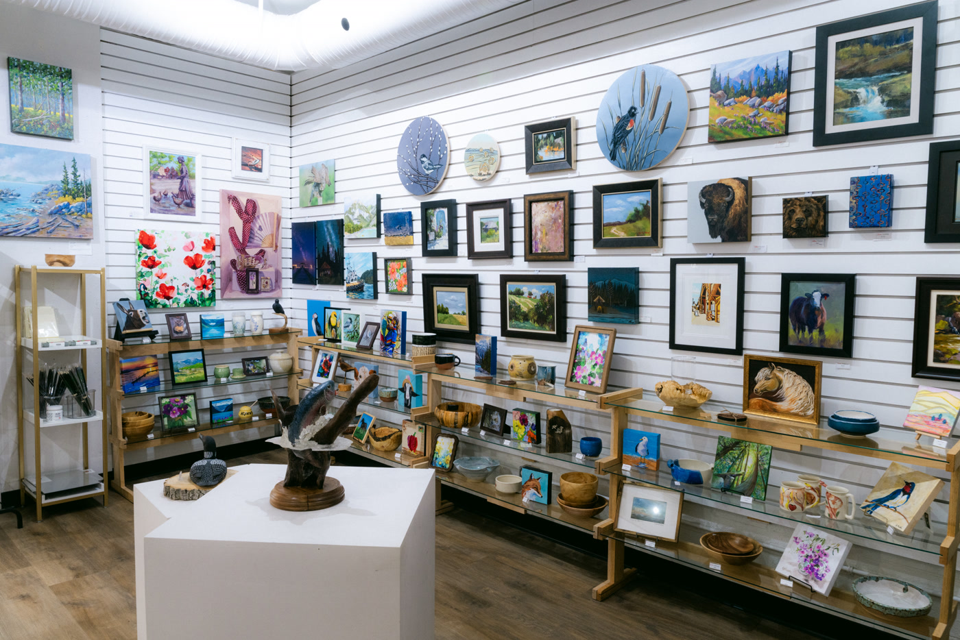 The corner of Route 22: a dark sculpture on a white plinth, wooden platters and a bison canvas above