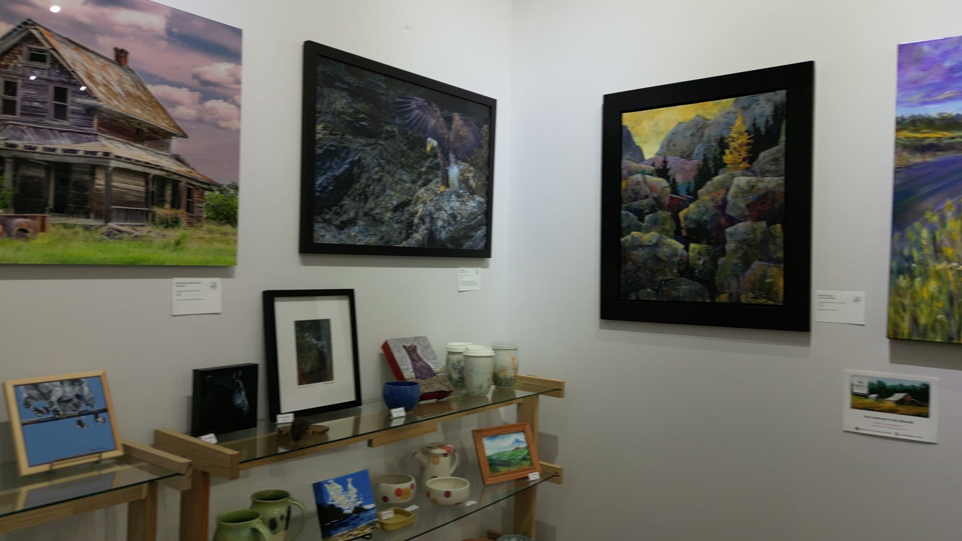 Turned wooden bowls and ceramics on the glass shelf below the paintings at Route 22