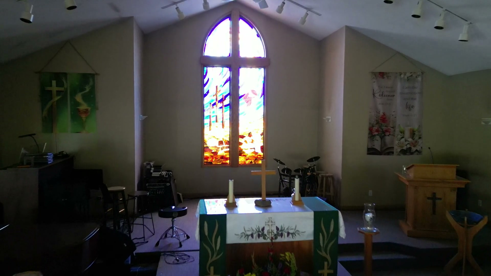 Pushing in from the chancel at half speed until the stained-glass window fills the frame — the three crosses, the hill beneath them and the tomb cut into the rock