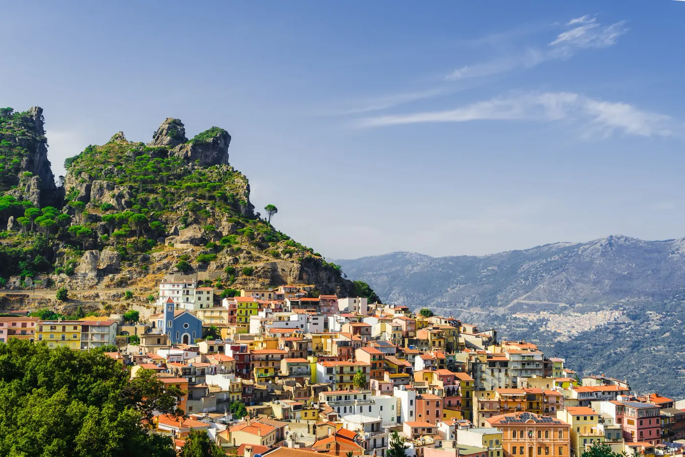 A cliffside village of terracotta roofs stacked below a rocky crag