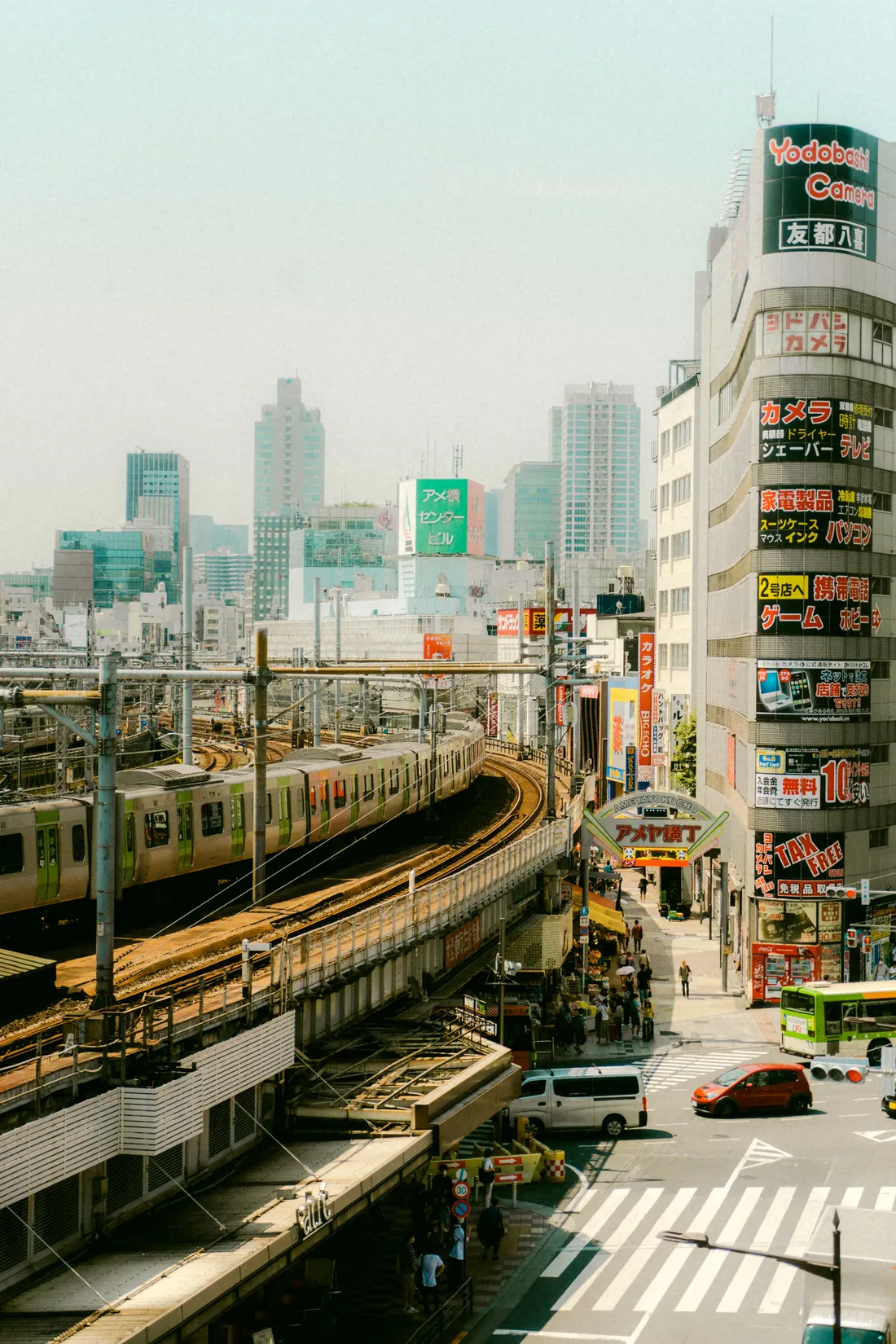 An elevated train curving past neon-signed buildings above a busy crossing