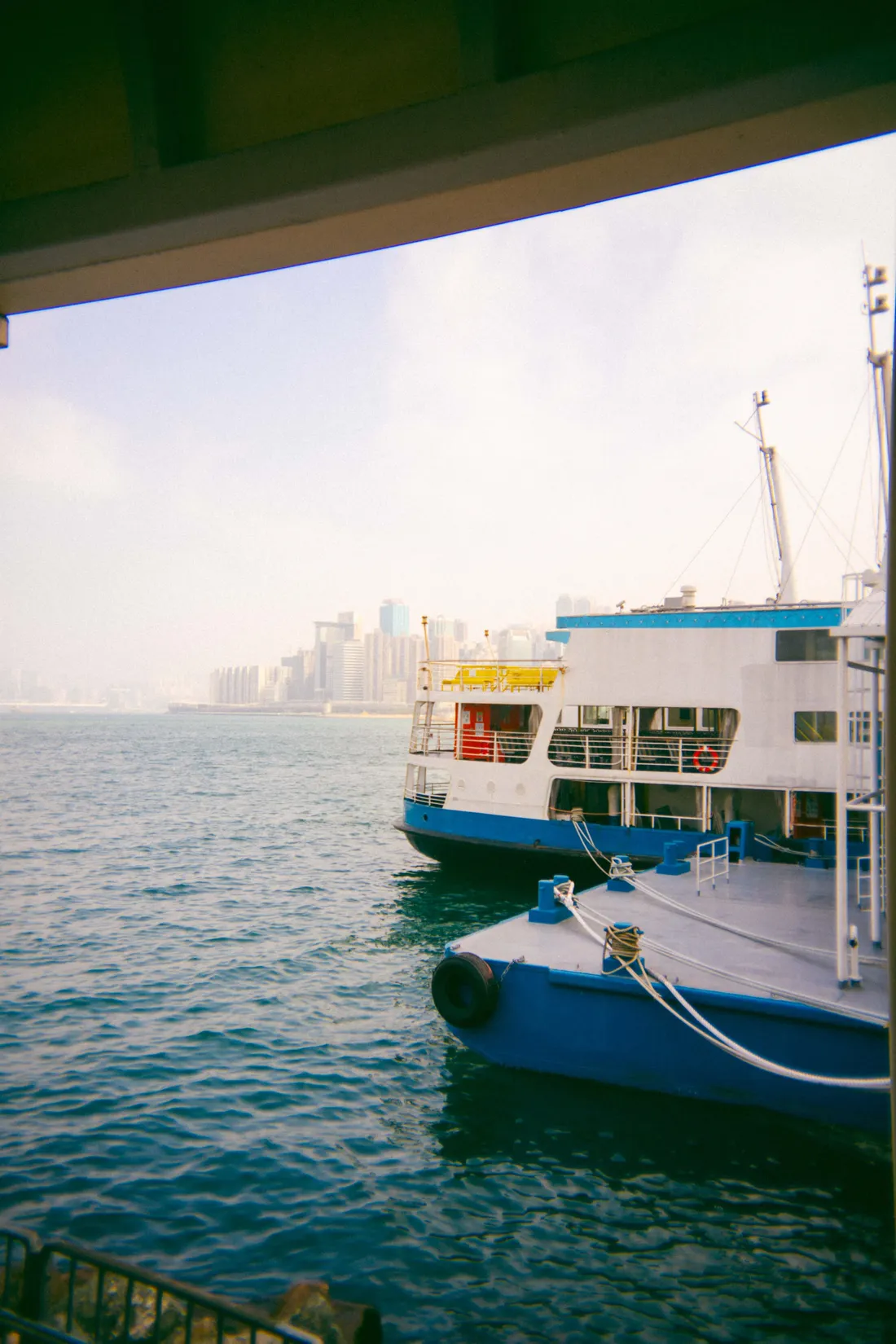 A blue and white ferry moored in a harbour, the skyline faint beyond