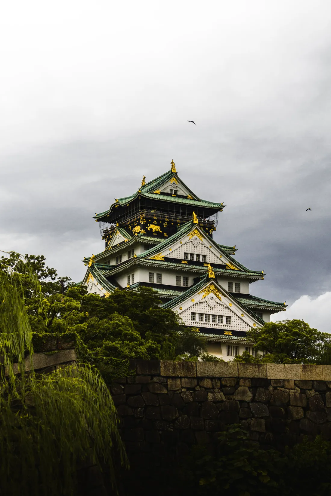 A tiered castle keep on a stone rampart under heavy storm cloud