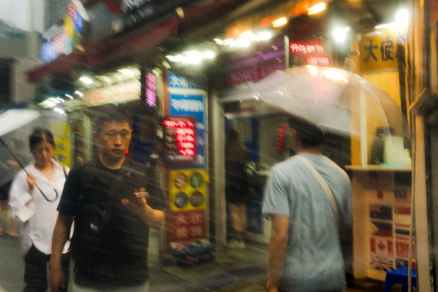 Shoppers passing a brightly lit night market stall hung with signs