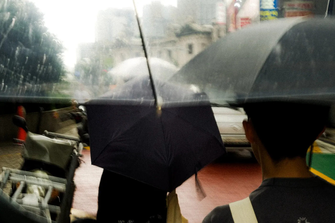 Umbrellas crowding a wet street, the frame blurred by rain and movement