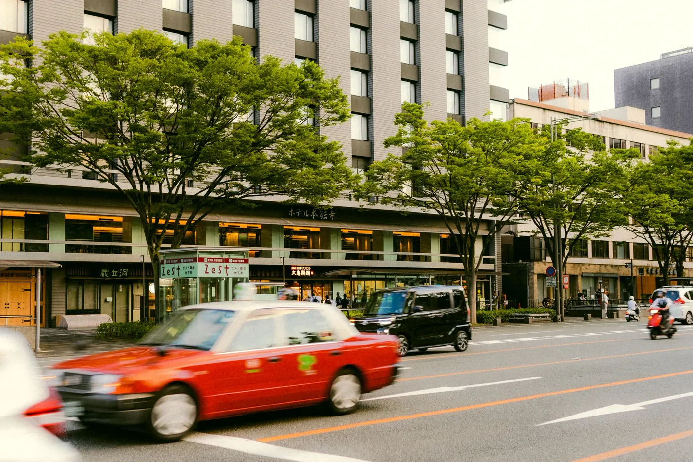 A red taxi panned in motion along a tree-lined city street