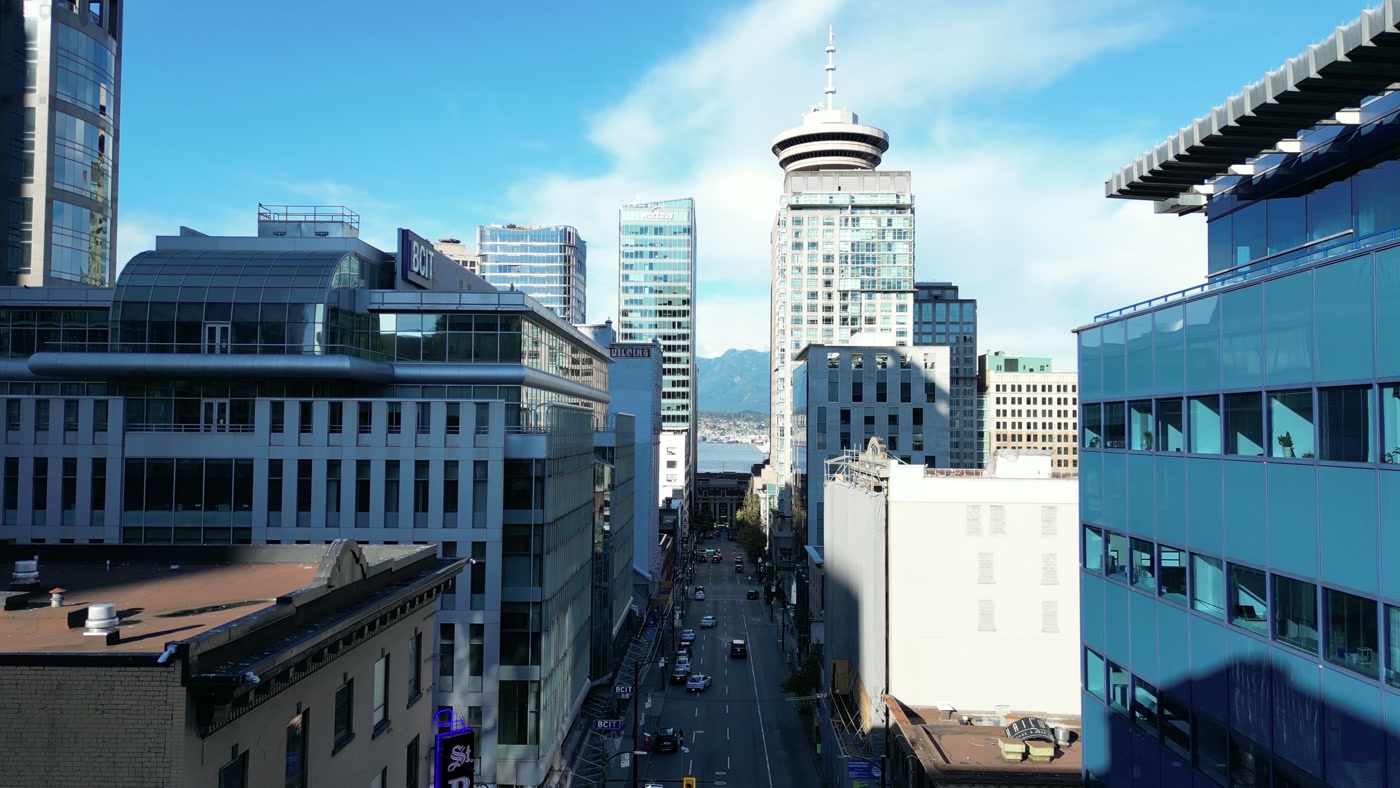 The north end of Seymour Street in Vancouver from above: Harbour Centre's Lookout, the harbour water and the North Shore mountains beyond, BCIT's building on the left, blue glass on the right