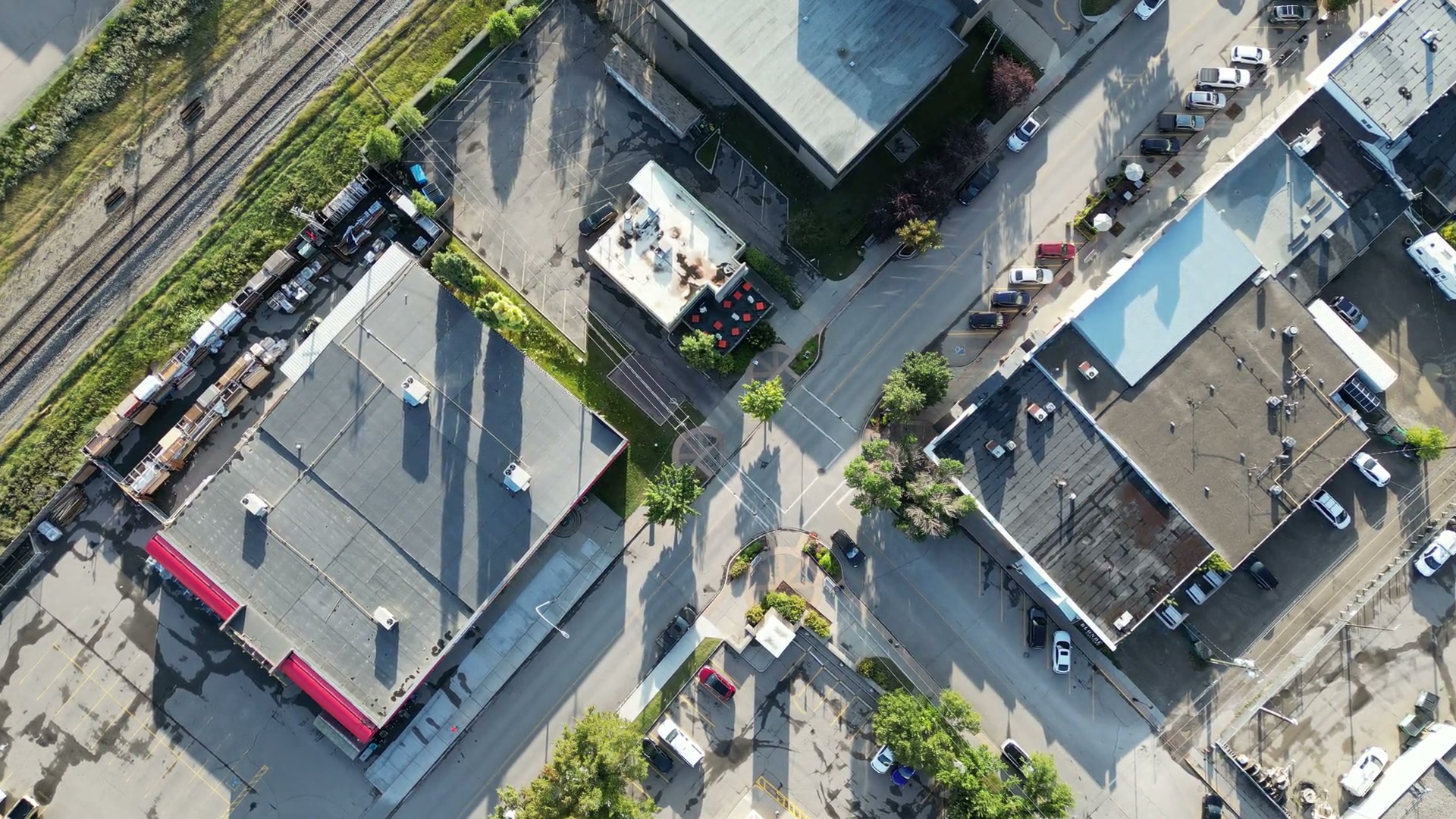Directly above Sunny Side Up on 1st Street West in Cochrane, the camera drifting over the restaurant's roof and red-tabled patio, the building next door, the tracks and a lot of parked cars