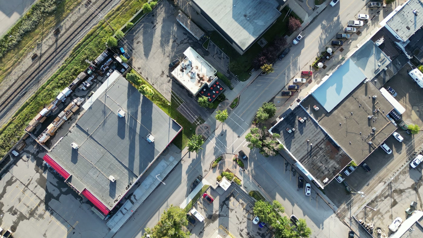 1st Street West in Cochrane from straight above: the rooftops of the block, the parked cars along the kerb and the rail line running past