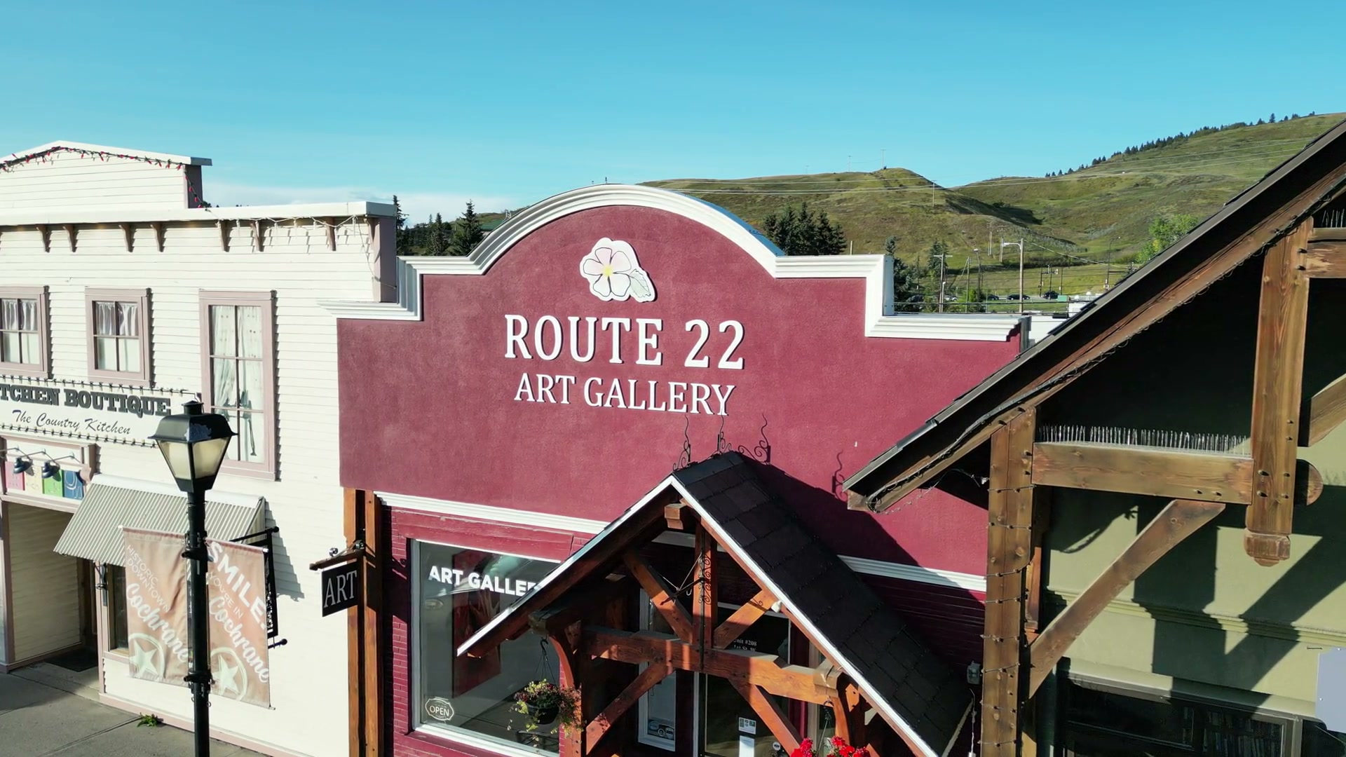 The heavy timber porch and lamp post beneath the Route 22 Art Gallery sign on 1 Street West, Cochrane