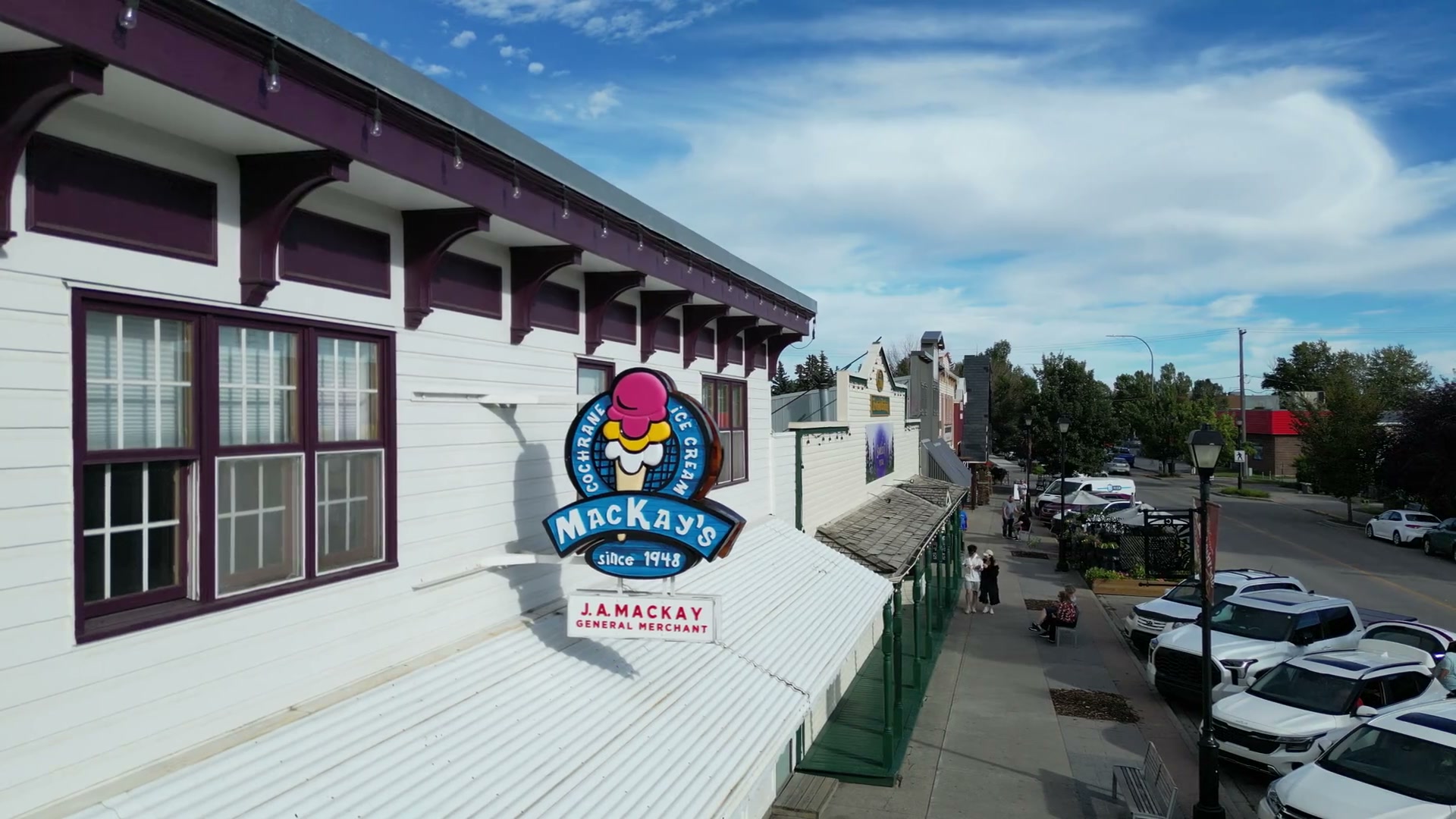 The MacKay's ice cream roundel held under the shop's deep-red eave brackets against a summer sky
