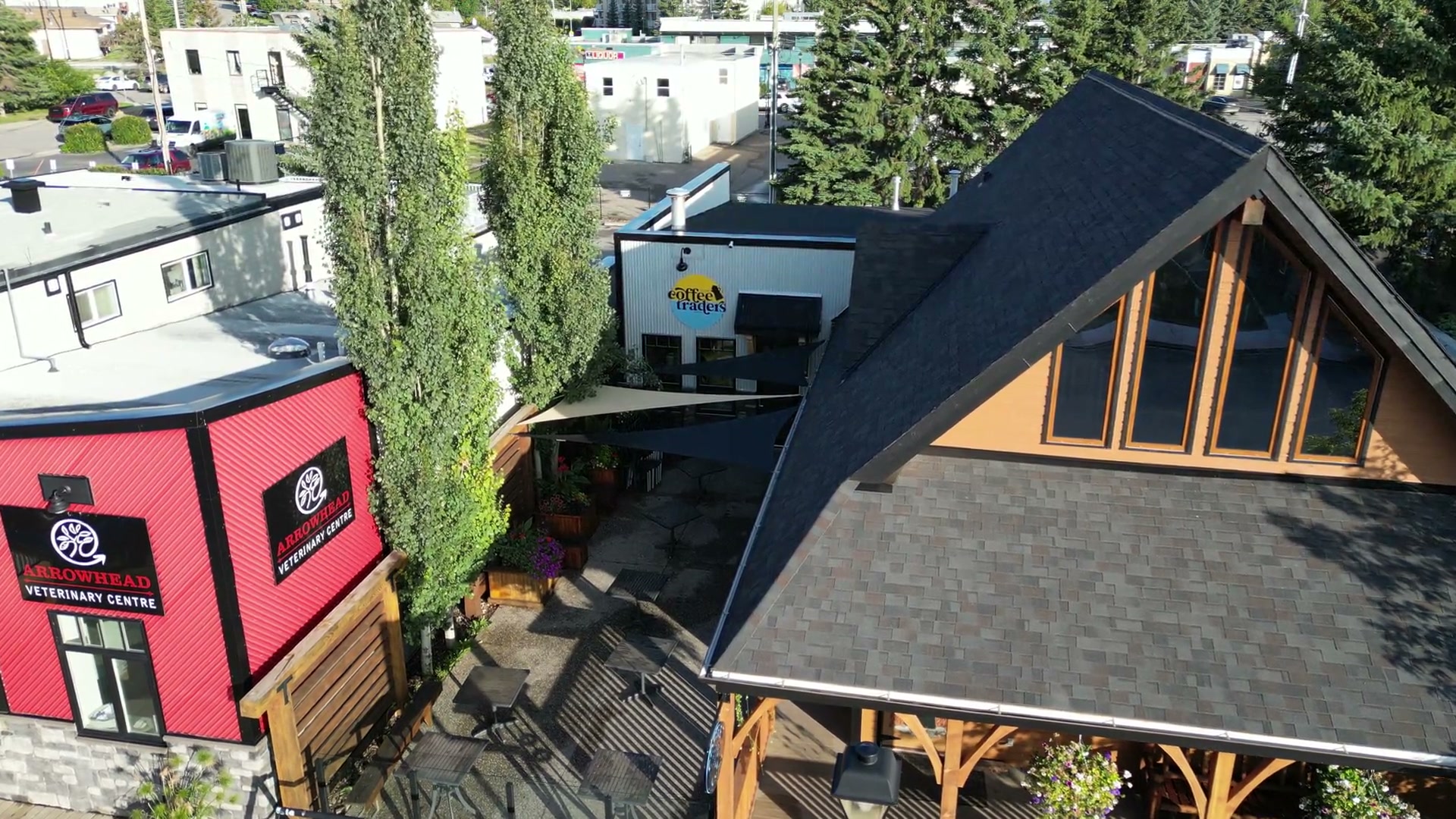 Moving in past the red clinic next door to Cochrane Coffee Traders toward the courtyard between it and the timber gable, the round sign on the corrugated wall and the poplars rising past the roofline