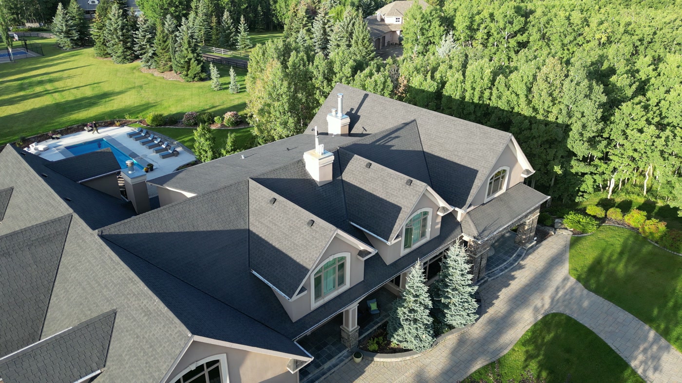 The estate's roofline and dormers from above, the pool terrace beyond — the edit's closer frame