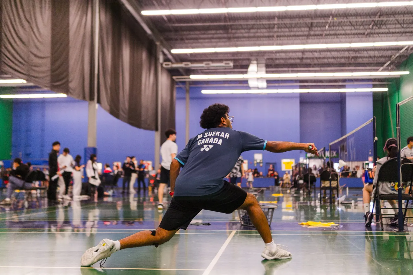 An athlete lunging through a throwing release inside an indoor field house