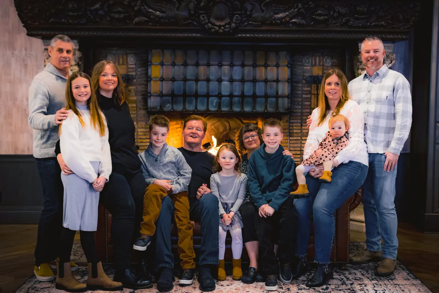A large family arranged in front of a carved fireplace for a portrait