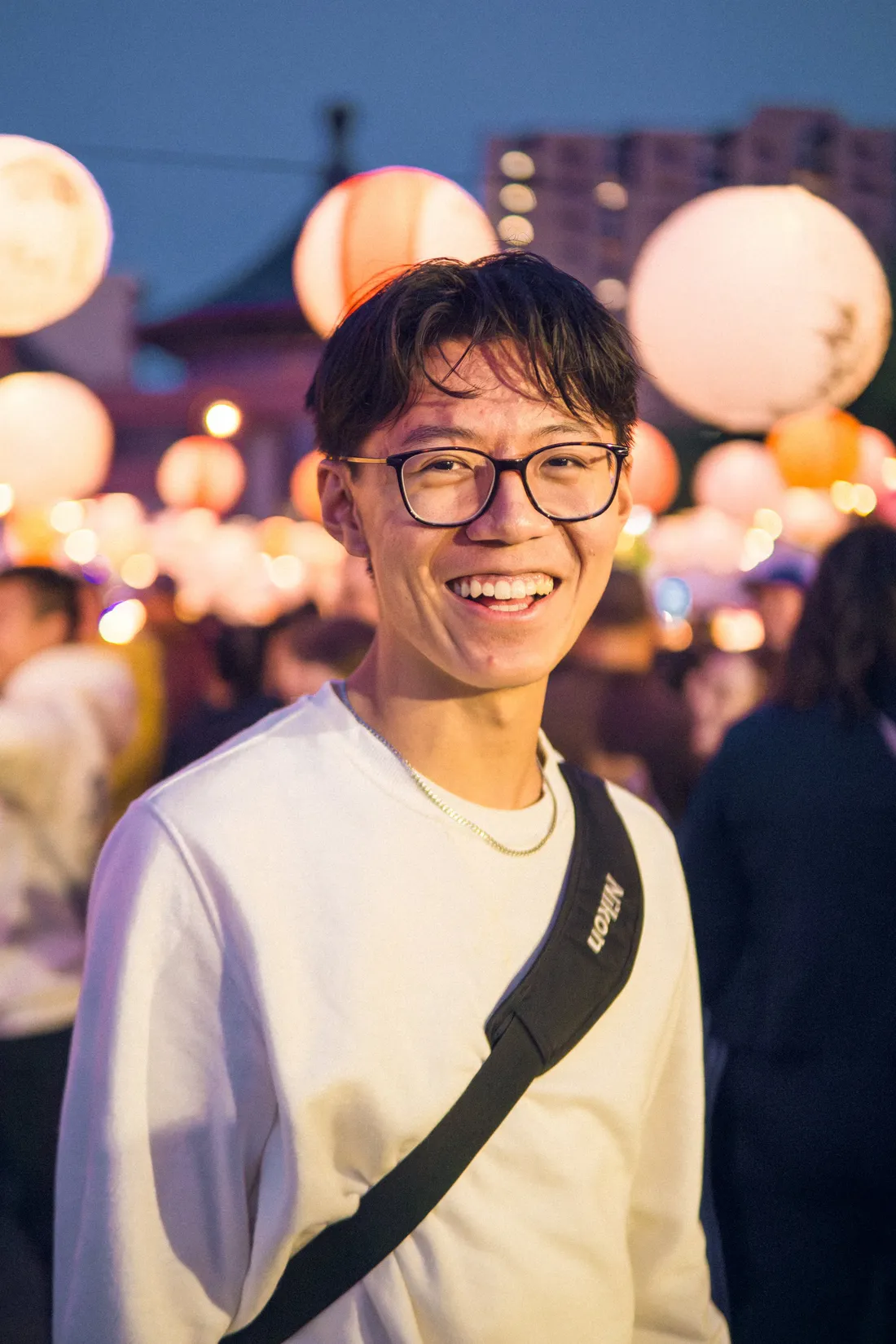 A smiling man among glowing paper lanterns at a night festival