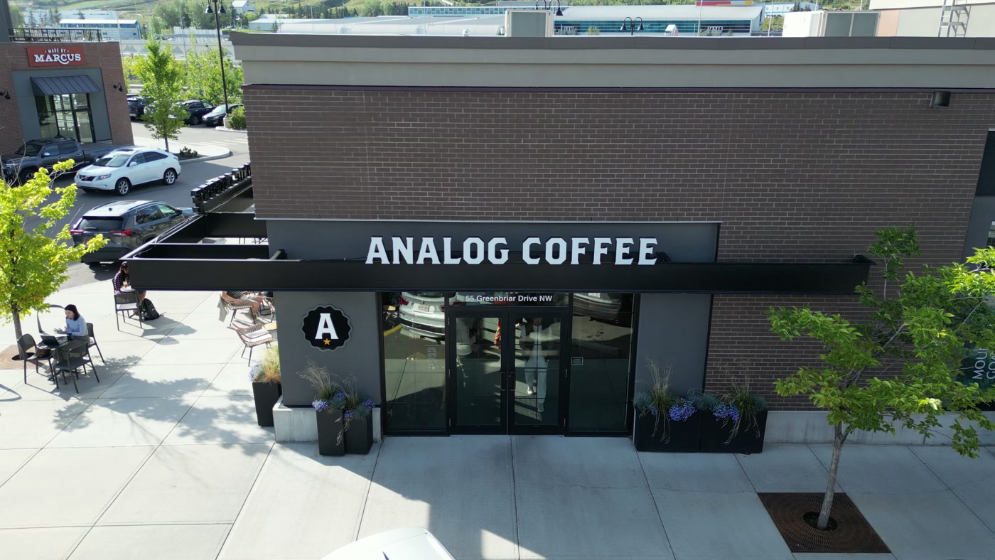 The black awning, the lettering and the A roundel from just above, with the patio chairs and planters below
